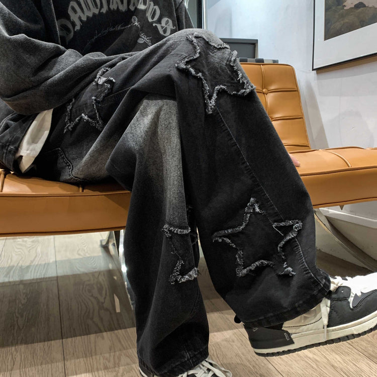 Black denim wide-leg pants with star patches and distressed knee rips
