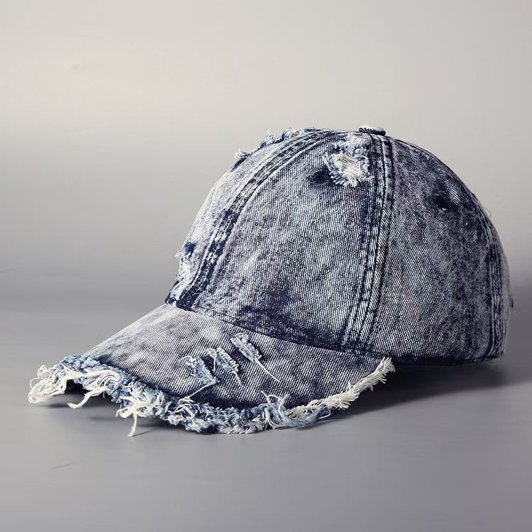 Washed denim baseball cap with embroidered logo detail and frayed brim, light wash.