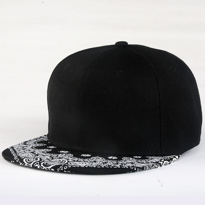 Black baseball cap with white paisley print brim, curved crown seams
