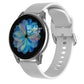 Smartwatch with silver case and white silicone band, black screen with blue flower graphic.