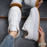 White lace-up sneakers with thick sole and tan gum outsole