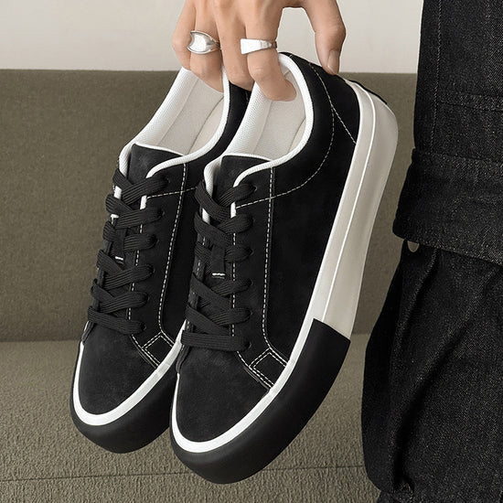 Black low-top sneakers with lace-up front, white contrast sole, and stitched panels