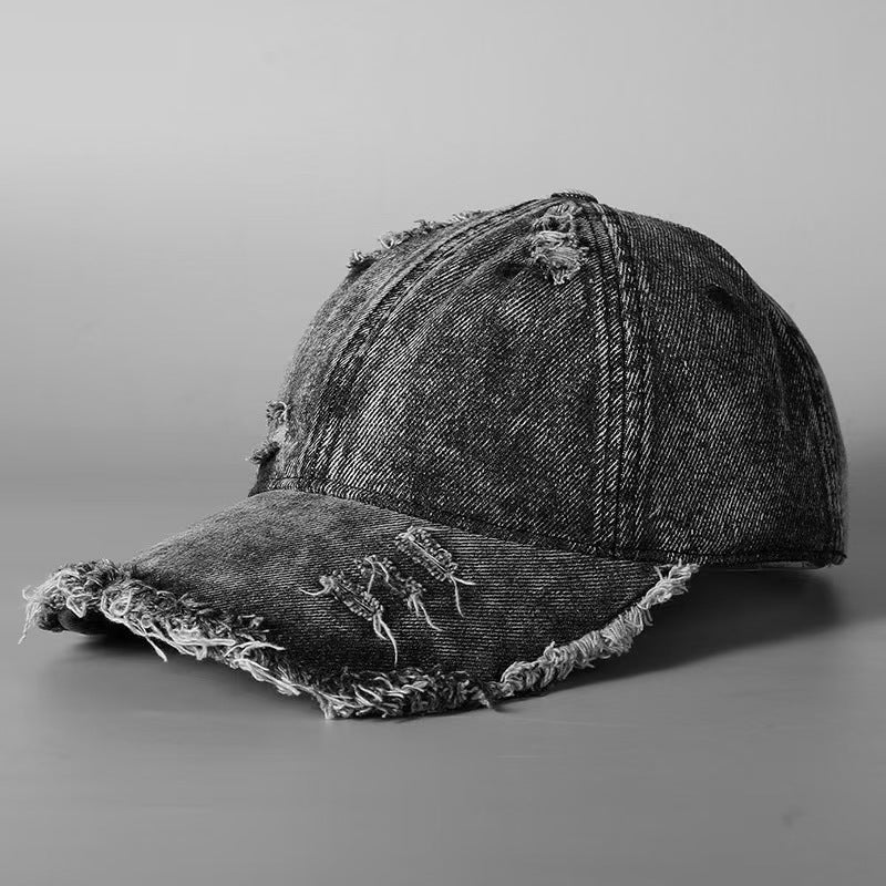 Washed denim baseball cap with distressed crown and frayed brim, dark wash.