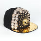Black baseball cap with gold brim, rhinestone skull and circular studded side panel