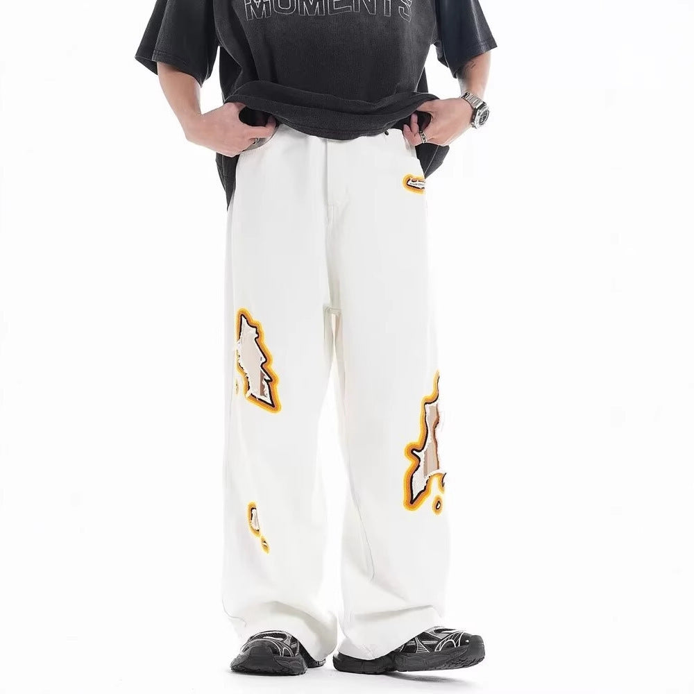 Loose white trousers with ripped embroidery patch detail near the hip