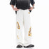 Loose white trousers with ripped embroidery patch detail near the hip