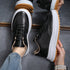Black lace-up sneakers with thick white sole and tan gum outsole