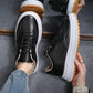 Black lace-up sneakers with thick white sole and tan gum outsole