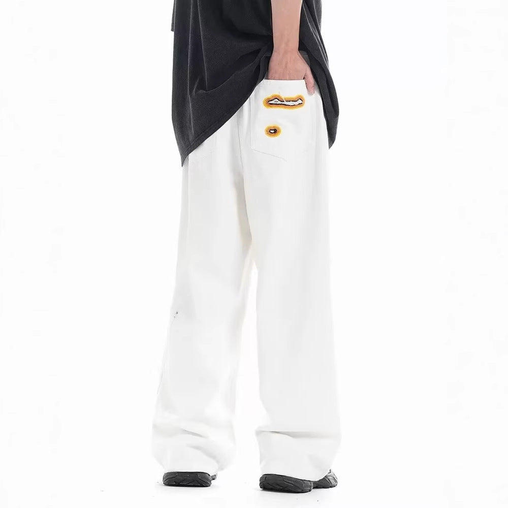 Loose white trousers with small ripped embroidery patch on the thigh